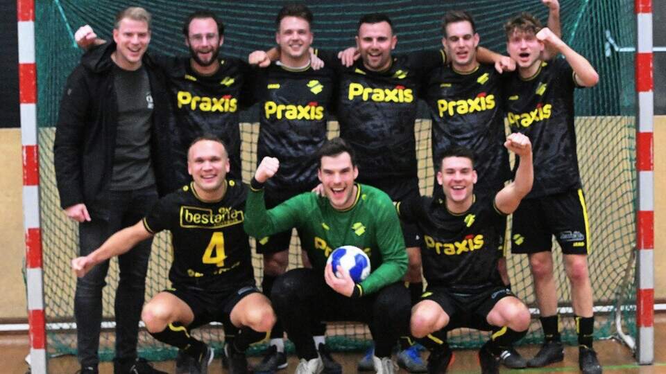 Zaalvoetbalploeg van de Boys viert een overwinning in de sporthal: spelers in zwart-gele shirts voor het doel, de keeper met de bal in zijn handen.