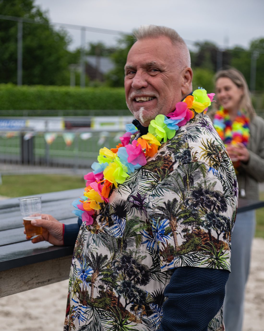 Bezoeker met bloemenkrans en een biertje op het zand tijdens Steenwijker Beach.