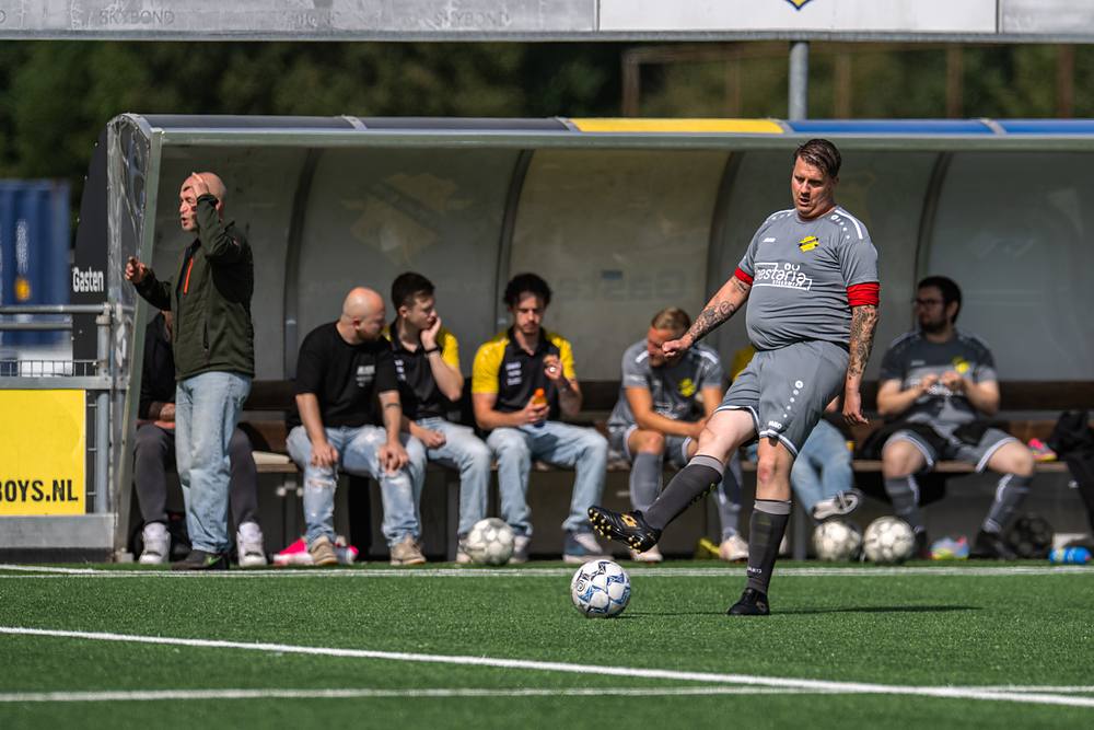 Wisselspelers kijken vanaf de dug-out toe terwijl een speler de bal aanneemt.
