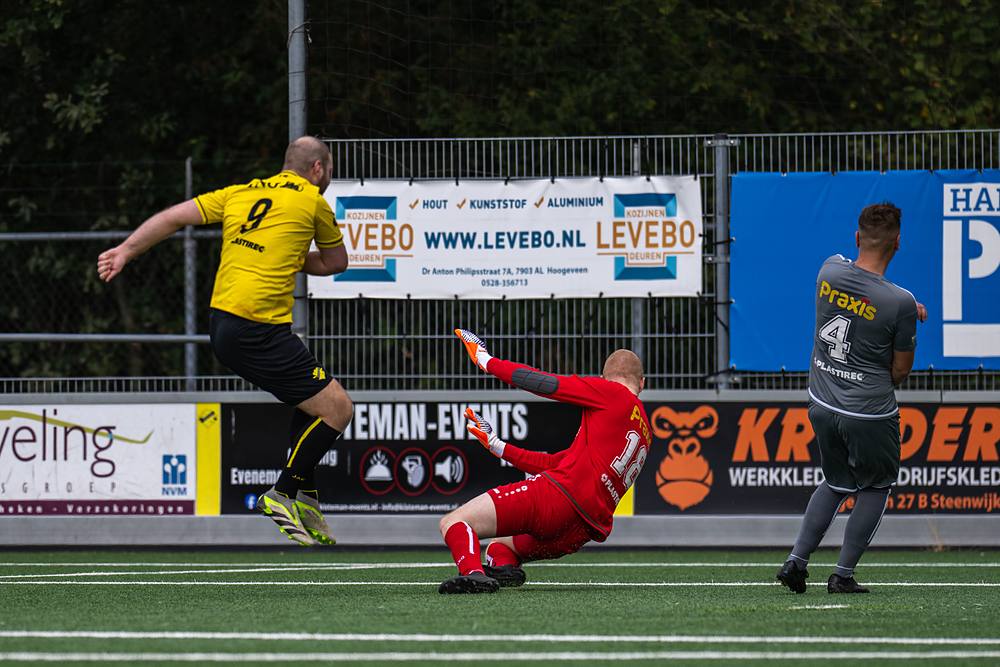 De keeper ligt op de grond nadat de bal langs hem gaat.