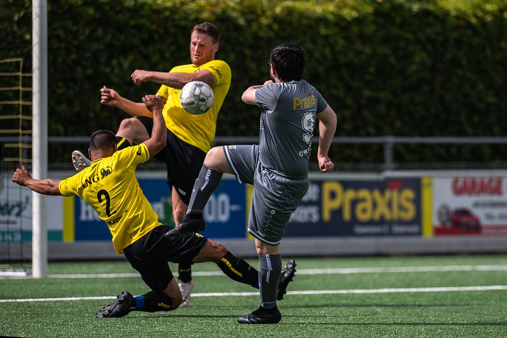 Sliding: een speler in het geel gaat er vol in op de bal.